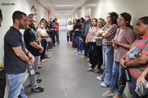 Montagem digital com dois registros das reuniões setoriais, na primeira há um corredor com pessoas enfileiradas lado a lado, uma fila está em frente à outra. Na segunda imagem, as pessoas estão reunidas em círculo em uma antessala. Nas duas imagens, as pessoas ouvem o coordenador-geral do SINJUS-MG, Alexandre Pires. Também estão presentes nas reuniões os diretores: Felipe Rodrigues ( dir. de Assuntos Jurídicos), Jonas Araújo (dir. de Assuntos Sociais, Culturais e de Saúde), Alexandre Gomes (dir. de Imprensa e Comunicação), Janaína Torres (dir. de Aposentados e Pensionistas) e Adriana Teodoro (dir. Administrativa).