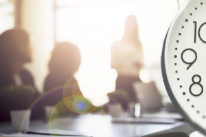 Arte com selo de “Urgente” no topo, informa no texto central que "sindicatos cobram nova reunião do GT de oito horas". A imagem mostra uma sala de reunião desfocada ao fundo e, em destaque, um relógio marcando as horas, simbolizando o tema da jornada de trabalho.