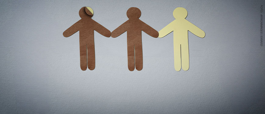 Imagem Acessível: A imagem traz três figuras humanas de papel, em cores diferentes, de mãos dadas, simbolizando diversidade racial. A primeira figura humana é de papel marrom, por baixo dela está uma figura em papel branco, a segunda figura é marrom e a terceira é bege claro. A imagem alerta para possíveis fraudes nas regras de fiscalização das candidaturas vinculadas às cotas raciais. Conteúdo textual: Eleições 2026 - Minuta do TSE ignora verificação racial obrigatória e coloca em risco política de cotas eleitorais.