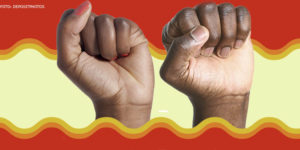 Dois punhos de pessoas negras em gesto de luta, um é de uma mulher e o outro é de um homem. Ao fundo, aplicados digitalmente, há adornos em formato de ondas em tons que variam do vermelho ao amarelo.