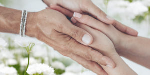 Imagem acessível: A imagem mostra mãos sobrepostas em um gesto de acolhimento e apoio, com flores brancas ao fundo. Em destaque, o texto “Você sabia que filiados ao SINJUS contam com Auxílio-Funeral?”, apresentando o benefício exclusivo aos filiados. Na base, a logomarca do SINJUS-MG.
