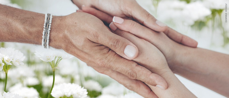 Imagem acessível: A imagem mostra mãos sobrepostas em um gesto de acolhimento e apoio, com flores brancas ao fundo. Em destaque, o texto “Você sabia que filiados ao SINJUS contam com Auxílio-Funeral?”, apresentando o benefício exclusivo aos filiados. Na base, a logomarca do SINJUS-MG.