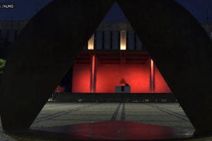 Vista noturna da ALMG (Palácio da Inconfidência), à frente do edifício, há uma escultura onde se vê um triângulo que remete à bandeira do estado de Minas. Pelo triângulo, pode-se ver o edifício iluminado em tons de vermelho. Conteúdo textual: Eleições 2022 - Na ALMG, ala progressista aumentou; no Congresso, cenário é obscuro.