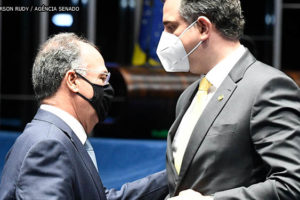 líder do governo e relator da PEC dos Precatórios, Fernando Bezerra (homem de pele clara, parcialmente calvo, usando óculos e uma máscara preta), conversa com o presidente do Senado, Rodrigo Pacheco (homem de pele clara, cabelos grisalhos e usando máscara branca) durante sessão no Senado.