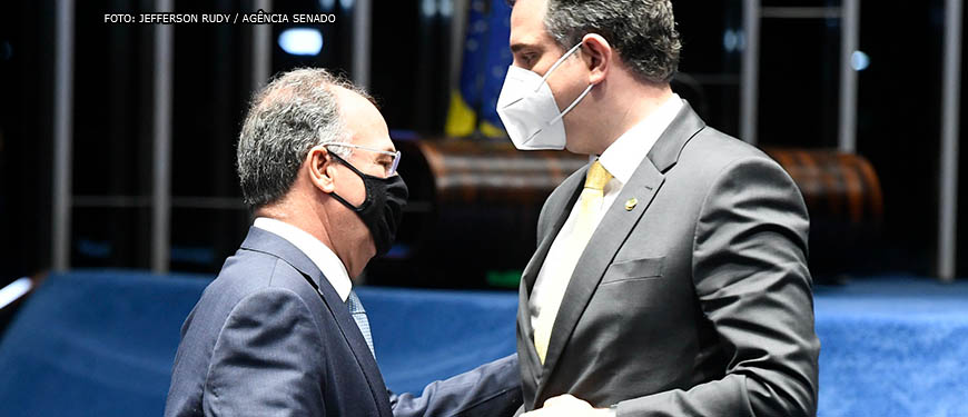 líder do governo e relator da PEC dos Precatórios, Fernando Bezerra (homem de pele clara, parcialmente calvo, usando óculos e uma máscara preta), conversa com o presidente do Senado, Rodrigo Pacheco (homem de pele clara, cabelos grisalhos e usando máscara branca) durante sessão no Senado.