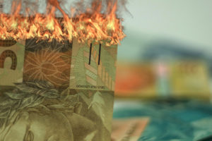 Nota de 50 reais queimando sinalizando a perda inflacionária
