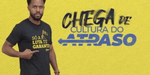 Arte de mobilização do SINJUS com fundo amarelo texturizado. À esquerda, homem negro, de cabelo curto e barba, veste camiseta preta com a frase “Só a luta te garante!” e aponta para a estampa. Ao centro, aparece o destaque “Chega de cultura do atraso”.Conteúdo textual: MOBILIZAÇÃO - SINJUS convoca categoria para acompanhar sessão do OE na próxima 4ªf.