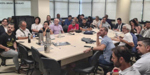Foto de uma sala com uma ampla mesa em que, ao redor, estão sentados representantes de entidades sindicais, entre eles os dirigentes do SINJUS Alexandre Pires e Felipe Rodrigues.