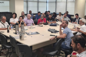 Foto de uma sala com uma ampla mesa em que, ao redor, estão sentados representantes de entidades sindicais, entre eles os dirigentes do SINJUS Alexandre Pires e Felipe Rodrigues.