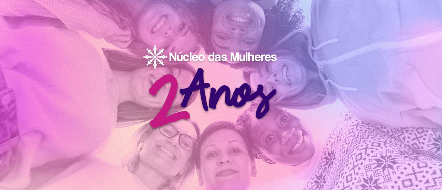 Foto com diversas mulheres abraçadas formando um círculo em tons de rosa e azul de 2º plano, no primeiro plano temos o conteúdo textual " Núcleo das mulheres" " 2 anos"