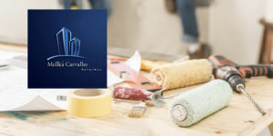 Imagem acessível: A imagem mostra uma mesa com ferramentas de construção, como rolo de pintura, fita adesiva e furadeira, com pessoas trabalhando ao fundo desfocado. O texto informa: “Garanta descontos em reformas e construções civis com o novo convênio do SINJUS”. Também aparece o logotipo da empresa Mellká Carvalho Reformas.