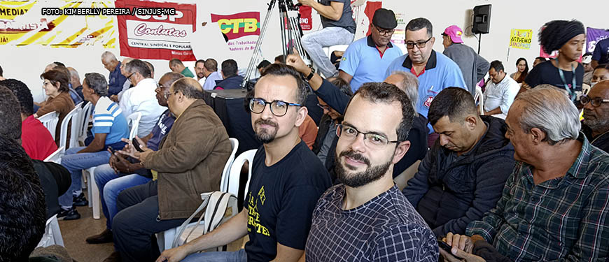 Em primeiro plano está o diretor de Assuntos Jurídicos, Felipe Rodrigues e ao seu lado está Alexandre Gomes, diretor de Comunicação e Imprensa do SINJUS-MG. Ambos estão entre representantes de movimento sindical em audiência pública realizada na Assembleia Legislativa de Minas Gerais. Conteúdo textual: ARTICULAÇÃO - SINJUS PARTICIPA DE AUDIÊNCIA PÚBLICA COM MINISTRO DO TRABALHO.