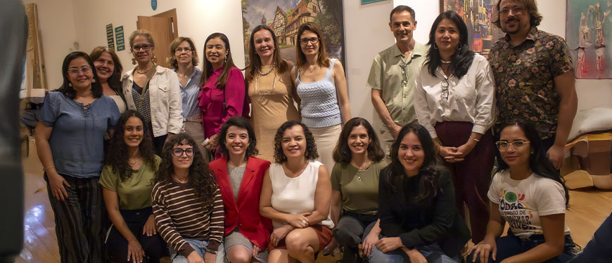 Imagem Acessível: Registro de dois momentos do evento Cinefem, do Núcleo das Mulheres do SINJUS-MG. Na parte superior, um músico toca piano, e abaixo aparece um grupo de participantes reunidos, sorrindo para a foto. Entre as filiadas e debatedores estão as diretoras Adriana Teodoro e Janaína Torres, que estão à frente da iniciativa. Conteúdo textual: SETEMBRO AMARELO - Cinefem discute as pressões que adoecem as mulheres a partir de Cisne Negro.