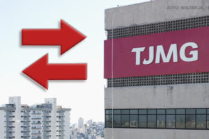 A imagem mostra o edifício do Tribunal de Justiça de Minas Gerais (TJMG), um prédio imponente com fachada de concreto e grandes janelas espelhadas. Sobreposto à imagem, há setas vermelhas apontando em direções opostas. Há indicando no texto a publicação da lista de pedidos de remoção deferidos. Ao fundo, pode-se ver edifícios residenciais e uma paisagem urbana de Belo Horizonte, evidenciando a localização em área central da cidade.