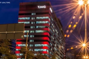 Edifício sede do TJMG na avenida Afonso Pena no período noturno, na avenida há muitas luzes de veículos automotores indicando um tráfego intenso.