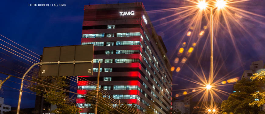Edifício sede do TJMG na avenida Afonso Pena no período noturno, na avenida há muitas luzes de veículos automotores indicando um tráfego intenso.