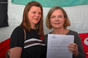 Imagem Acessível: Arlete Rogoginski, coordenadora-geral da Fenajud, mulher branca de cabelos e olhos castanhos entregwa documento para a presidenta do Partido dos Trabalhadores (PT), Gleisi Hoffmann, mulher branca de cabelos loiros e olhos azuis.