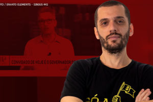 Imagem com filtro vermelho, nela há uma TV onde está a imagem de um vídeo do governador Romeu Zema em uma entrevista, ele é um homem branco, de cabelos brancos, sem barba e usa óculos). À frente está a foto colorida do coordenador-geral do SINJUS-MG, Alexandre Pires, ele é um homem branco, de cabelos e barba castanhos bem curtos; ele está com os braços cruzados e veste uma camisa preta de luta do Sindicato.