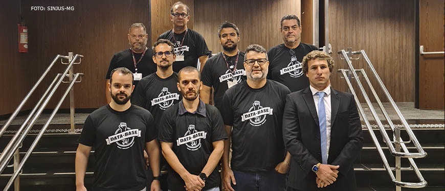 : Fotografia diurna onde os diretores do Sinjus e outros sindicalistas estão na entrada do auditório do Órgão Especial, onde se vê um ambiente formal e os mesmos com semblante de seriedade.