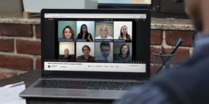 Imagem Acessível: A imagem mostra um homem sentada à mesa assistindo, em um notebook, a uma live no YouTube com oito participantes em janelas de vídeo. O título da transmissão é “Reforma Administrativa e PEC 66: ameaças e desafios”. No rodapé da imagem, em destaque, está o texto: “SINJUS denuncia riscos contidos na Reforma Administrativa e na PEC 66”.