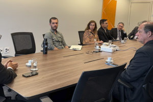 Imagem acessível: A imagem mostra uma reunião do Comitê Gestor de Atenção Integral à Saúde de Magistrados e Servidores do TJMG, com representantes reunidos em torno de uma mesa. No centro da arte, o título “Comitê debate ações de saúde e SINJUS cobra melhorias nas condições de trabalho do TJMG”. Na base da imagem, aparece o logo do SINJUS-MG.