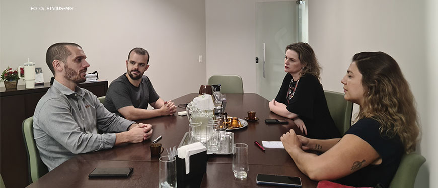 Na foto estão o coodenador-geral do SINJUS-MG, Alexandre Pires e o diretor de Assuntos Jurídicos do Sindicato, Felipe Rodrigues. Os dois dirigentes estão em uma mesa de reunião com as representantes do Sindalemg, a coordenadora-geral do Sindalemg, Gisele Paola Antonioli, e a coordenadora administrativa, Daniela Johannes Rad Fonseca. Conteúdo textual: Atuação conjunta SINJUS e Sindalemg unem forças em favor de Datas-Bases e Auxílios e contra o RRF.