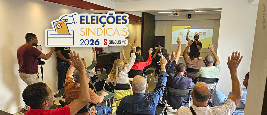 A imagem registra o momento da Assembleia-Geral Extraordinária (AGE) do SINJUS-MG, na qual foi definida a composição da Junta Eleitoral que conduzirá as Eleições Sindicais 2026. Na foto, filiadas e filiados aparecem com as mãos levantadas, votando e participando ativamente da decisão coletiva. Ao fundo, um telão exibe o tema da AGE. O texto central informa: "Definida a composição da Junta Eleitoral que irá conduzir as Eleições 2026 do SINJUS". O selo “Eleições Sindicais 2026” complementa a identidade visual da campanha, simbolizando transparência, representatividade e participação da categoria.