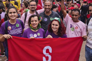 Diretores do SINJUS posam junto de manifestantes com a bandeira do Sindicato, aparecem na imagem: Adriana Teodoro, diretora de Assuntos Sociais e Saúde, Alexandre Gomes, diretor de Imprensa e Comunicação, Wagner Ferreira, diretor de Assuntos Jurídicos e vereador de BH, e Jonas Pinheiro, diretor de Formação Política.