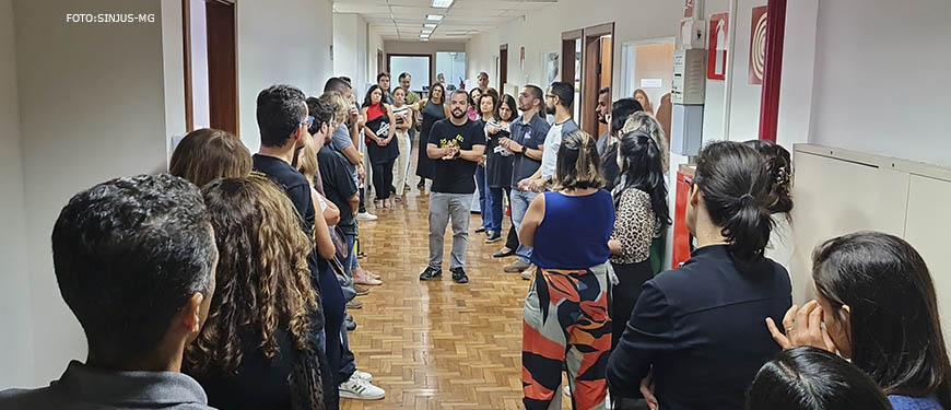 Fotografia da parte interna do Èdificio Afonso Pena 1500 onde aparecem os diretores do Sinjus em um corredor com chão de madeira, paredes brancas, eles estão dialogando com os servidores, o ambiente é de atenção.