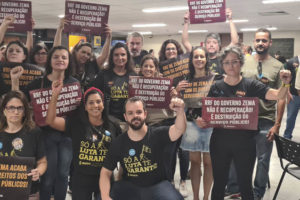 Fotografia de grupo formado por dirigentes sindicais e servidores em protesto contra o RRF na Assembleia Legislativa. A maioria das pessoas veste preto e carrega cartazes com frases sobre os impactos do RRF no funcionalismo público e na sociedade.