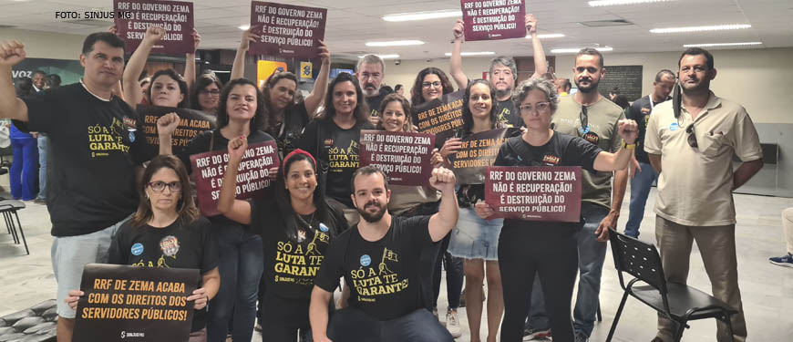 Fotografia de grupo formado por dirigentes sindicais e servidores em protesto contra o RRF na Assembleia Legislativa. A maioria das pessoas veste preto e carrega cartazes com frases sobre os impactos do RRF no funcionalismo público e na sociedade.