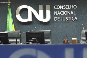 Mesa diretiva do plenário do CNJ, em destaque está o letreiro em aço inox onde se lê a "CNJ - Conselho Nacional de Justiça".