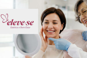 Imagem acessível: A Imagem divulga o novo convênio do SINJUS-MG, mostrando ao fundo a foto de uma clínica de estética focando em uma mulher adulta sorrindo enquanto se olha em um espelho que segura, aparentando satisfação com a própria aparência, e ao lado dela, uma profissional mais velha toca suavemente seu rosto com expressão acolhedora, em um ambiente claro que transmite cuidado e bem-estar. No centro da imagem, está o logotipo do convênio “Eleve-se, Estética e Bem-Estar”, com símbolo de borboleta, e logo abaixo lê-se o texto em destaque: “Fique em dia com a sua autoestima com o novo convênio do SINJUS”, enquanto no topo aparece o texto “Clínica de Estética”.