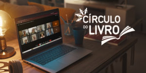 Imagem acessível: A arte apresenta o título “Círculo do Livro aborda pertencimento e valorização da singularidade” sobre a imagem de uma mesa em ambiente acolhedor, com um notebook exibindo uma reunião virtual com diversos participantes. Ao redor aparecem luminária, caneca, lápis, livro e fones de ouvido. A peça identifica a atividade “Mulheres que Correm com os Lobos”, traz a marca do Círculo do Livro e o símbolo do SINJUS na parte inferior.