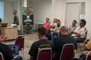 Imagem Acessível: A fotografia retrata um grupo de pessoas em uma sala em prol do Coletivo de Negras e Negros da Fenajud. Conteúdo Textual: ANTIRRACISMO COLETIVO DE NEGRAS E NEGROS DA FENAJUD REALIZA PRIMEIRO ENCONTRO EM BH