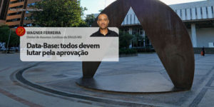 Fachada da Assembleia Legislativa de Minas Gerais. À frente está a foto do colunista Wagner Ferreira, diretor de Assuntos Jurídicos do SINJUS-MG (homem negro de cabelos grisalhos bem curtos, vestido com camisa social). Conteúdo textual: Data-base – Todos devem lutar pela aprovação.