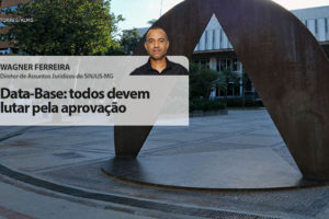 Fachada da Assembleia Legislativa de Minas Gerais. À frente está a foto do colunista Wagner Ferreira, diretor de Assuntos Jurídicos do SINJUS-MG (homem negro de cabelos grisalhos bem curtos, vestido com camisa social). Conteúdo textual: Data-base – Todos devem lutar pela aprovação.