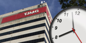 A imagem mostra a fachada do prédio do TJMG vista de baixo para cima, com um grande relógio marcando oito horas em primeiro plano simbolizando o debate sobre a jornada de trabalho. No topo lê-se “Intransigência”.