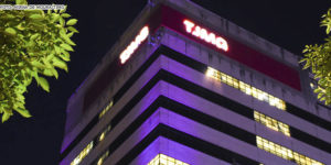 Vista noturna da fachada da sede do TJMG iluminada com luzes rosadas. Conteúdo textual: TJMG divulga intimação de candidatos à PV 2021 com documentos incorretos.