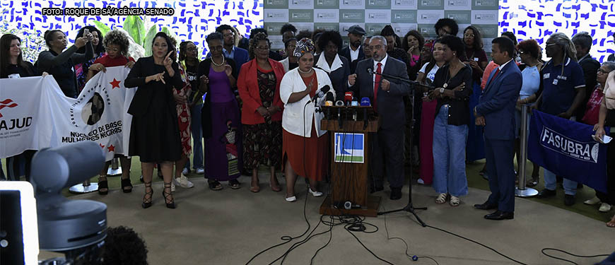 Imagem Acessível: Coletiva de imprensa do Lançamento da Frente Parlamentar Mista Antirracismo (FPMA), o Coordenador da FPMA no Senado Federal, senador Paulo Paim discursa na presença de militantes de Movimentos Negros e parlamentares.