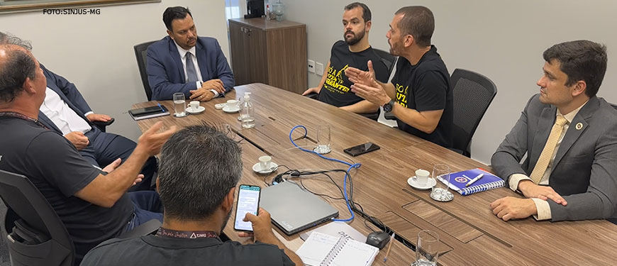 Na imagem há uma mesa onde estão reunidos o coordenador-geral do SINJUS, Alexandre Pires e o diretor de Assuntos Jurídicos do SINJUS-MG; também fazem parte da mesa os dirigentes do SINDOJUS/MG e do Serjusmig, além dos representantes da presidência do TJMG.