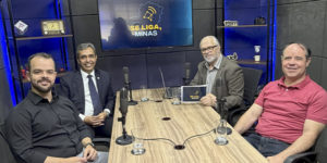 Imagem acessível: A imagem mostra o registro fotográfico do último episódio do podcast Se Liga, Minas. Em destaque, o título diz: "Legado de JK atravessa gerações e inspira debate no Se Liga, Minas". Na base da imagem, aparece a logomarca do SINJUS-MG.