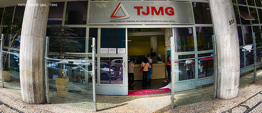 Fachada da Unidade Goiás do TJMG, com placa em aço inox com a marca do Tribunal e letreiro com a identificação do local "Secretaria do Tribunal de Justiça de Minas Gerais" .