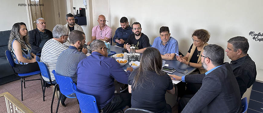 Mesa de reunião com dirigentes de sindicatos e associações, nesta mesa estão Alexandre Pires, coordenador-geral do SINJUS-MG e Felipe Rodrigues, diretor de Assuntos Jurídicos do Sindicato. Conteúdo textual: LUTA CONJUNTA - SINDICATOS E ASSOCIAÇÕES SE UNEM PARA COMBATER O RRF EM MINAS.