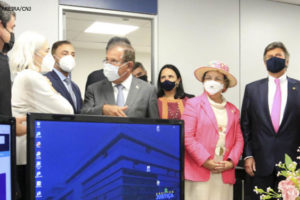 Foto de homens e mulheres brancos, em trajes sociais, reunidos na inauguração da Ouvidoria Nacional da Mulher, em uma sala com computadores. Em destaque, estão a ouvidora nacional da Mulher, Tânia Regina Silva Reckziegel, o presidente do CNJ, ministro Luiz Fux, e o presidente do Superior Tribunal de Justiça (STJ), ministro Humberto Martins.Conteúdo textual: Proteção – CNJ inaugura Ouvidoria Nacional da Mulher.