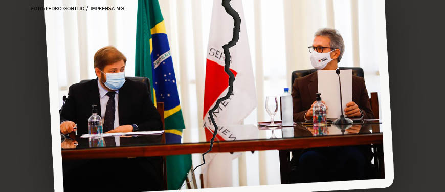 Imagem manipulada digitalmente simula uma foto rasgada ao meio. Do lado esquerdo há um homem branco, barbeado, com cabelo em tom acaju e traje social preto (Agostinho Patrus), do lado direito há um homem grisalho, barbeado, em traje social cor de vinho. Os dois estão em uma mesa usando máscaras de proteção contra covid-19.