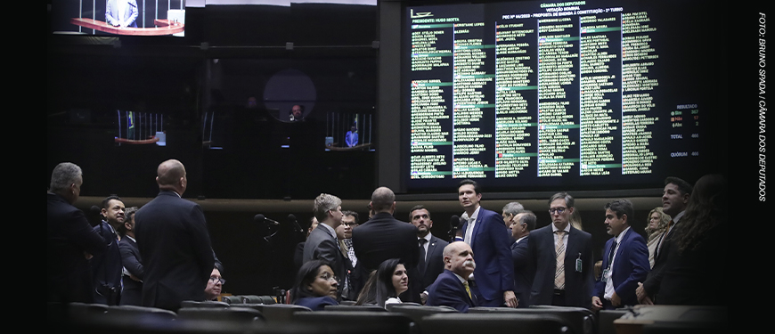 Deputados reunidos no plenário da Câmara em frente ao painel de votação eletrônica. A legenda informa que a Reforma Previdenciária foi barrada após forte mobilização sindical, durante a votação da PEC 66.