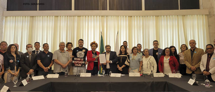 Posicionados atrás de uma grande mesa, lideranças sindicais e o presidente da ALMG, deputado Agostinho Patrus, posam para foto segurando o documento elaborado por entidades representantes dos servidores públicos mineiros.