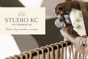 A imagem mostra uma mulher negra segurando uma câmera fotográfica e ajustando o foco em um ambiente iluminado. Sobre a imagem, o texto diz: “Eternize seus melhores momentos com o novo convênio de fotografia do SINJUS”. Abaixo, o logotipo do Studio KC Fotografia, acompanhado do slogan “Onde a luz encontra a emoção”. No canto superior esquerdo, está o título “Serviço”, e na base da imagem, o logotipo do SINJUS-MG.