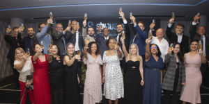 A imagem mostra os integrantes da nova diretoria do SINJUS-MG reunida em um evento de posse, todos vestidos formalmente erguendo taças em um brinde coletivo. No topo lê-se “Unidade”. O texto principal informa: “SINJUS-MG inicia novo ciclo de lutas com posse da gestão 2026-2029”. A cena representa a cerimônia de posse da Diretoria Colegiada e do Conselho Fiscal do sindicato, marcada pela celebração, renovação do compromisso com a categoria e defesa dos direitos das servidoras e dos servidores do Judiciário mineiro.